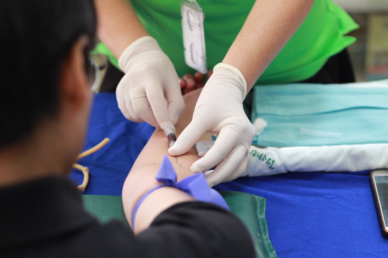 who-we-are A healthcare professional administering an injection to a patient's arm during a medical procedure.