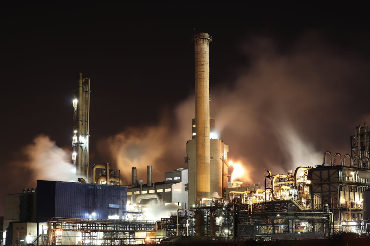 team-01 A nighttime view of an industrial factory with smokestacks emitting smoke, highlighting energy production and pollution.