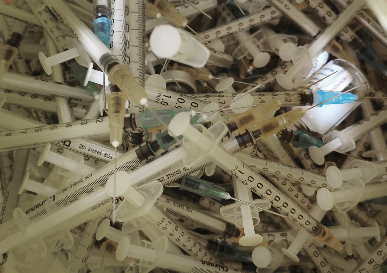 Close-up view of numerous medical syringes and vaccine vials used for immunization.